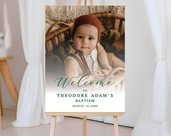 May include: Welcome to Theodore Adam's Baptism sign with a photo of a baby boy in a brown hat and a wicker basket. The sign is white with green text and the date August 16, 2024.