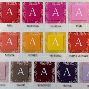 May include: A color chart featuring various shades of red, pink, orange, yellow, and purple. Each color is displayed on a square with the letter "A" in white. The colors are labeled with their names, such as "Dark Red" and "Lilac".