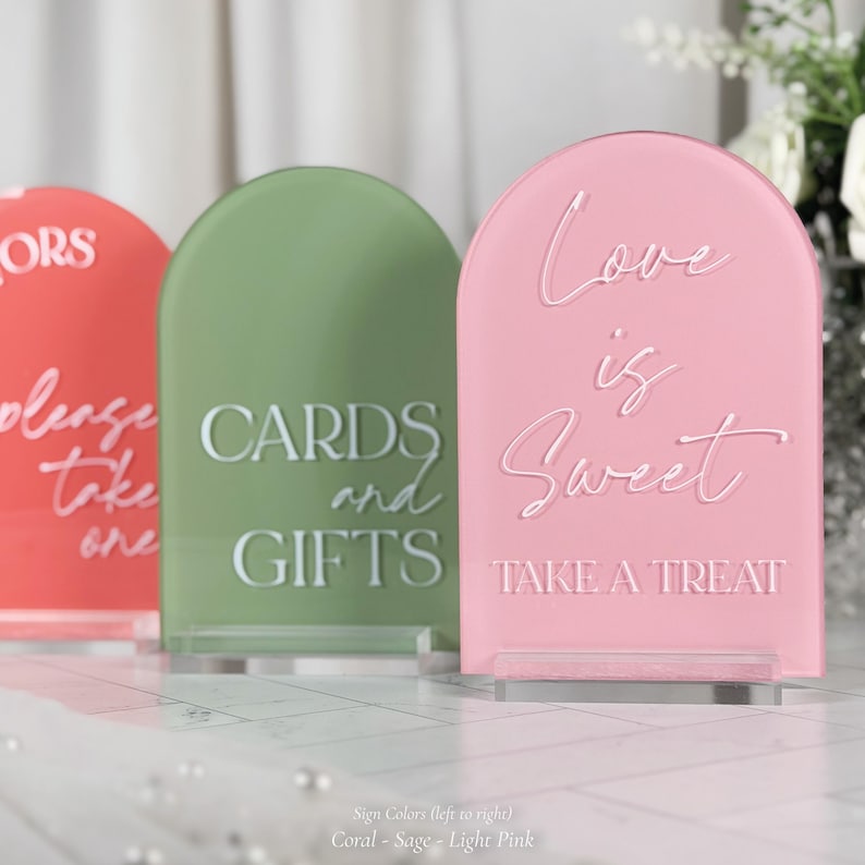 three different colored signs with text on them, placed on a white surface.