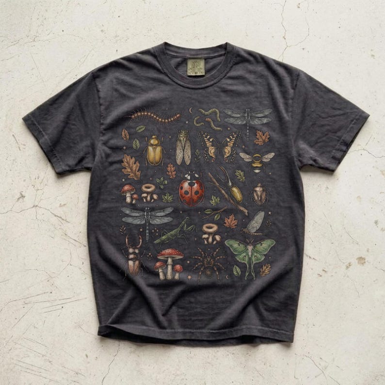 A vintage cottagecore print featuring a detailed collection of insects and woodland foliage. The layout centers on a large ladybug, surrounded by a centipede, dragonflies, a golden beetle, a cicada, a butterfly, a bumblebee, a praying mantis, a stag beetle, a spider, and a green luna moth. Interspersed among the detailed bugs are various red and brown mushrooms, autumn oak leaves, twigs, and tiny mystical stars. The artwork utilizes muted earthy tones for a classic nature aesthetic.