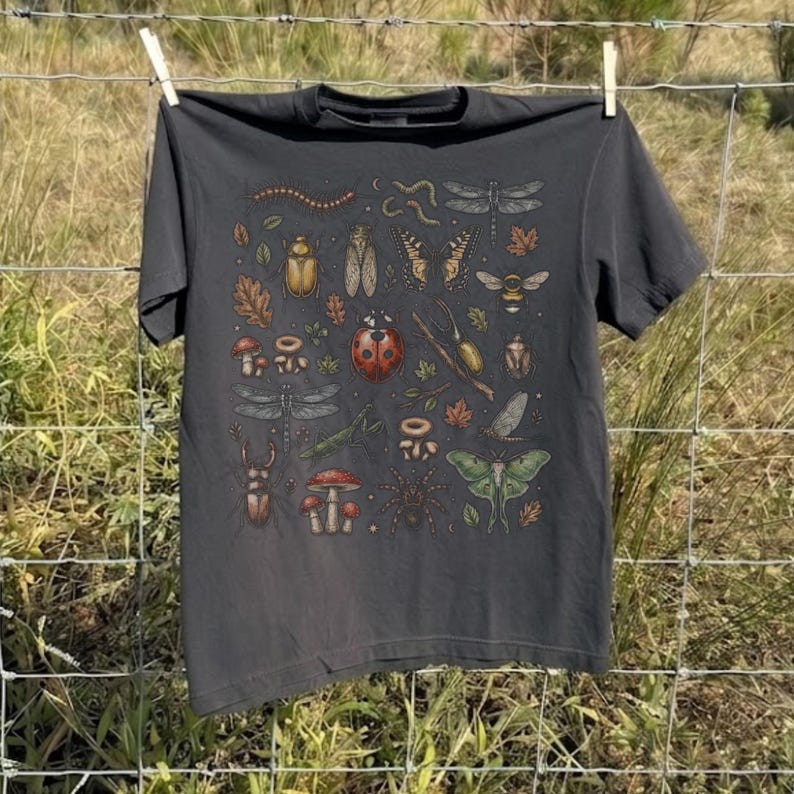 A vintage cottagecore print featuring a detailed collection of insects and woodland foliage. The layout centers on a large ladybug, surrounded by a centipede, dragonflies, a golden beetle, a cicada, a butterfly, a bumblebee, a praying mantis, a stag beetle, a spider, and a green luna moth. Interspersed among the detailed bugs are various red and brown mushrooms, autumn oak leaves, twigs, and tiny mystical stars. The artwork utilizes muted earthy tones for a classic nature aesthetic.