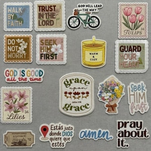 May include: A collection of decorative patches and stickers with inspirational quotes and floral designs. Includes patches with phrases like "Walk by Faith," "Trust in the Lord," and "God is Good." Features a bicycle, tulips, and a candle.