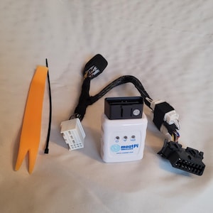 以下が含まれることがあります： 黒い上部を備えた白い「meatPi electronics」デバイス。さまざまな黒と白のコネクタ、オレンジ色のプラスチックツール、黒いケーブルタイに囲まれています。 デバイスには3つの青いインジケーターライトがあります。