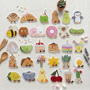 May include: A collection of embroidered patches featuring various cute characters including food items like a croissant, donut, taco, and boba tea, alongside animals like a penguin, bee, and duck, plus plants and a sun, all with smiling faces.