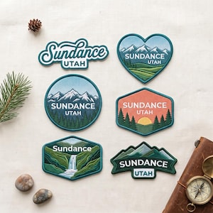 May include: Six embroidered patches featuring Sundance, Utah themes. Designs include a script logo, a heart-shaped mountain scene, a circular mountain landscape, a hexagonal sunset view, a waterfall landscape, and a mountain range banner with text.