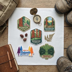 May include: Six embroidered patches featuring Redwood National Park designs, a brass compass, three small pinecones, and a fern leaf. The patches display various forest scenes, redwood trees, and text including Redwood National Park Est. 1968.