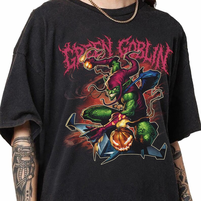 May include: Black t-shirt featuring a Green Goblin graphic. The design shows the Green Goblin character with a pumpkin bomb and a glider. The text "GREEN GOBLIN" is displayed in a stylized font above the character.