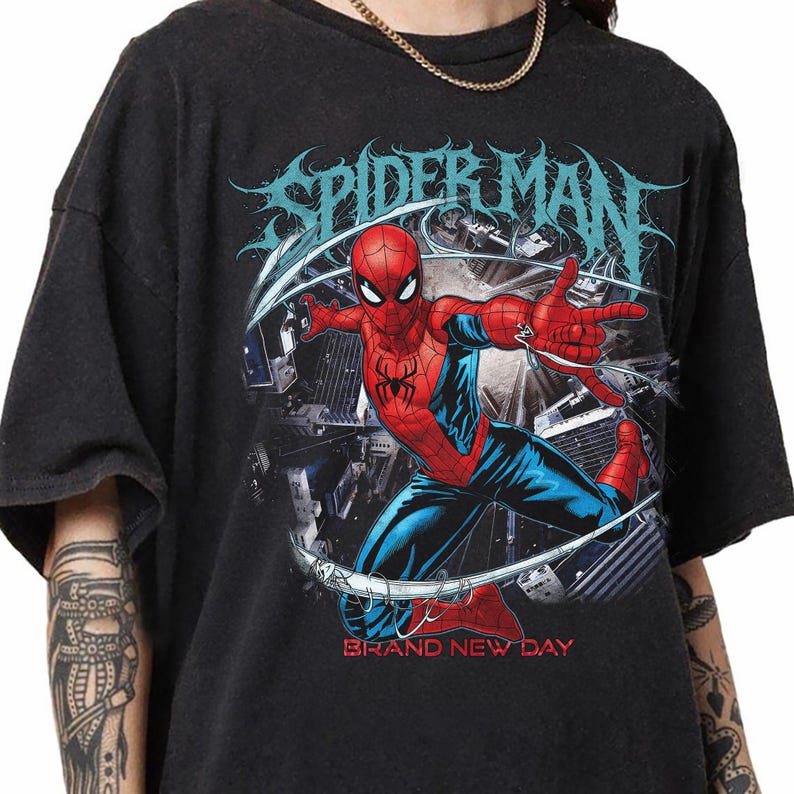 May include: Black t-shirt featuring a graphic of Spider-Man in a dynamic pose, with the words "SPIDER-MAN" in a stylized font above. The phrase "BRAND NEW DAY" is printed below the image. The superhero is depicted in his classic red and blue suit.