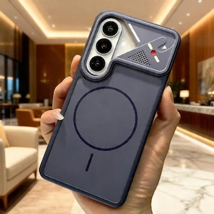 Op de afbeelding: Een donkerblauwe telefoonhoes met een uniek ontwerp. De hoes heeft een camera-uitsparing met drie lenzen, een luidspreker en een rode accentkleur. Een cirkelvormig ontwerp en een lijn bevinden zich op de achterkant.