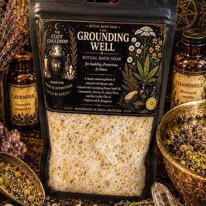 May include: A black pouch of The Grounding Well ritual bath soak featuring gold text and botanical illustrations. The label lists ingredients including Epsom salts, hemp seed oil, chamomile, yarrow, St. John's wort, cedarwood, and bergamot oil.