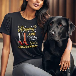 May include: A black short-sleeved t-shirt featuring a graphic print with gold glitter text that reads Stepping into my June birthday with God's grace & mercy, accompanied by an illustration of legs in red high heels and a small gold crown.