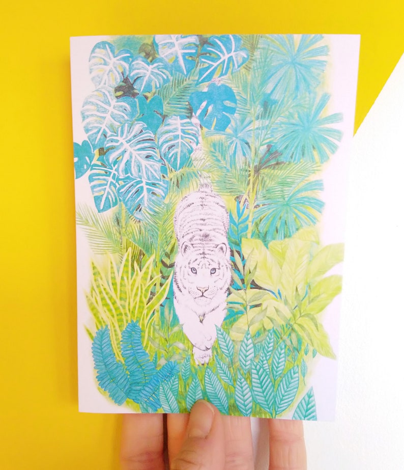 May include: A white tiger illustration walks through a lush, green and turquoise jungle. The artwork features detailed foliage and a striking contrast between the tiger and its environment. The background is a bright yellow and white.