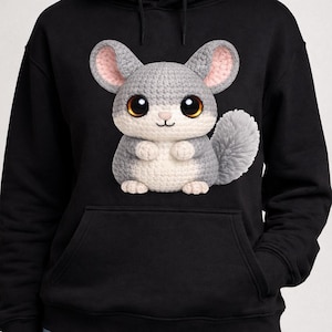May include: A black hooded sweatshirt featuring a large, centered graphic of a crocheted chinchilla. The chinchilla has grey and white yarn texture, large dark brown eyes, pink inner ears, and a fluffy tail, depicted in a seated position.