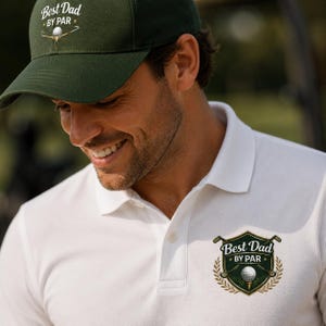May include: A dark green baseball cap and a white polo shirt. The cap features a white graphic of a golf ball on a tee with the text Best Dad By Par. The shirt has a matching embroidered crest logo with golf clubs and the text Best Dad By Par.