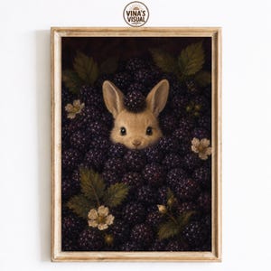 May include: A framed wall art print featuring a light brown rabbit head peeking out from a dense pile of dark purple blackberries. The scene includes green leaves and small white flowers scattered among the fruit, with a single berry on the rabbit's head.