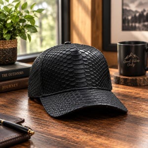 Pode incluir: Um boné de beisebol preto com um padrão texturizado semelhante a escamas em toda a superfície. O boné possui uma copa estruturada e uma aba curva, exibindo um design consistente e repetitivo que imita a aparência de escamas.