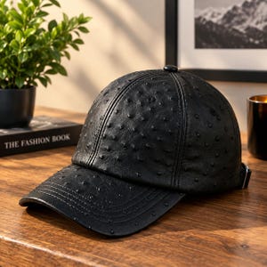 Pode incluir: Um boné de beisebol preto com um acabamento em couro texturizado estilo avestruz. O boné apresenta uma coroa estruturada com seis painéis, uma aba curva com detalhes de costura e uma tira de ajuste com fivela de metal na lateral.