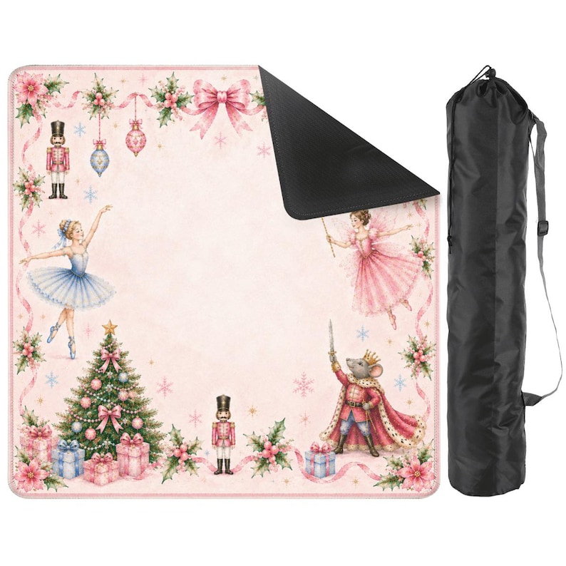May include: A pink picnic blanket with a black underside, featuring a Nutcracker theme. The design includes a Christmas tree, ballerinas, nutcrackers, and a mouse king. A black carrying bag is included.