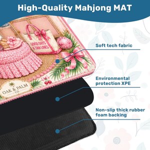 May include: A high-quality Mahjong mat with a pink and white design featuring a beach theme. The mat has a soft tech fabric, environmental protection XPE, and a non-slip thick rubber foam backing. The mat has the text "GOOD DAYS & TAN LINES".