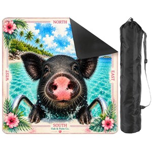 May include: A square outdoor blanket featuring a black pig in a swimming pool with tropical palm trees and hibiscus flowers. The border includes the text NORTH, SOUTH, EAST, WEST, and Oak & Palm Co. A black carrying bag with a strap is included.