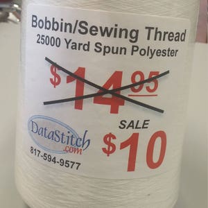 May include: A white spool of 25,000 yard spun polyester sewing thread. The spool has a label that says "Bobbin/Sewing Thread 25000 Yard Spun Polyester" and has a price tag with a sale price of $10. The original price of $14.95 is crossed out.