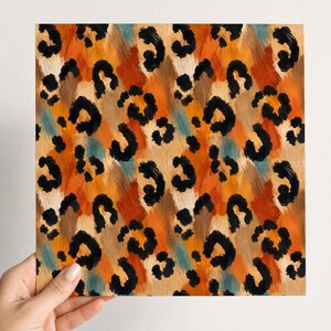 May include: A square sheet featuring a repeating leopard print pattern with black spots layered over a textured background of blended orange, tan, brown, and teal brushstrokes. The design displays a painterly aesthetic with visible strokes.