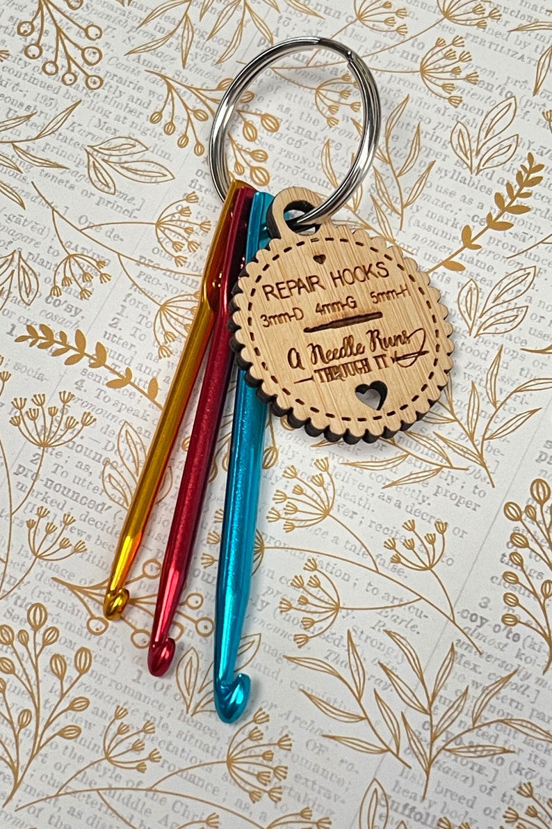 May include: A set of four crochet hooks, attached to a key ring, with a wooden tag that reads "Repair Hooks 3mm-D 4mm-G 5mm-H A Needle Runs Through It". The hooks are yellow, orange, red, and blue.