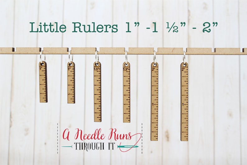 Pode incluir: Seis r&eacute;guas de madeira com an&eacute;is de metal pendurados numa barra de madeira. As r&eacute;guas medem 2,5 cm, 3,8 cm e 5 cm de comprimento. O texto "Little Rulers 1" - 1 1/2" - 2" est&aacute; no topo da imagem. O texto "A Needle Runs THROUGH IT" est&aacute; na parte inferior da imagem.