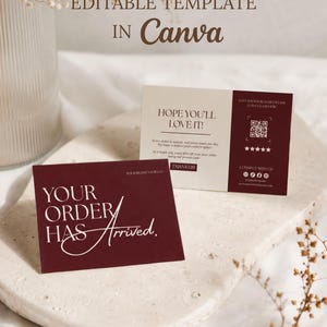 May include: Two rectangular business cards featuring a deep burgundy and cream color scheme. The front card displays the text YOUR ORDER HAS Arrived. The back card includes the text HOPE YOU'LL LOVE IT!, a QR code, and social media icons.