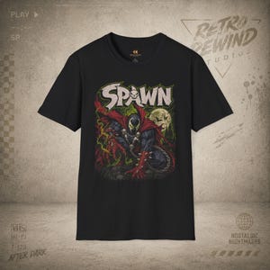 Könnte beinhalten: Schwarzes T-Shirt mit einem Spawn-Motiv. Das Design zeigt das Wort "Spawn" in einer verwitterten Schriftart, eine Comic-Illustration der Figur und einen Hintergrund bei Mondschein. Das T-Shirt hat kurze Ärmel.