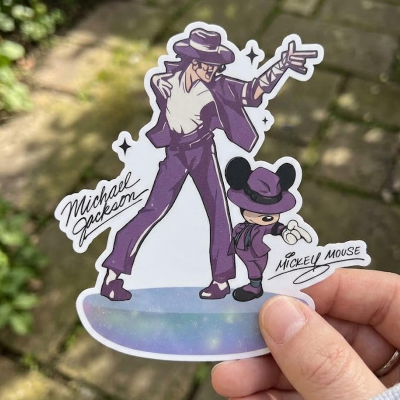 Pode incluir: Um adesivo com uma ilustra&ccedil;&atilde;o roxa de Michael Jackson de terno e chap&eacute;u, posando. Ao lado, um personagem do Mickey Mouse com uma roupa combinando. O adesivo tem o texto "Michael Jackson" e "Mickey Mouse".