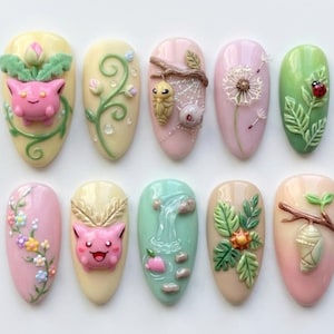 May include: A set of ten almond-shaped press-on nails featuring 3D relief designs. The collection includes pastel-colored bases decorated with sculpted elements such as pink creatures, green vines, a dandelion, a ladybug, a waterfall, and cocoons.