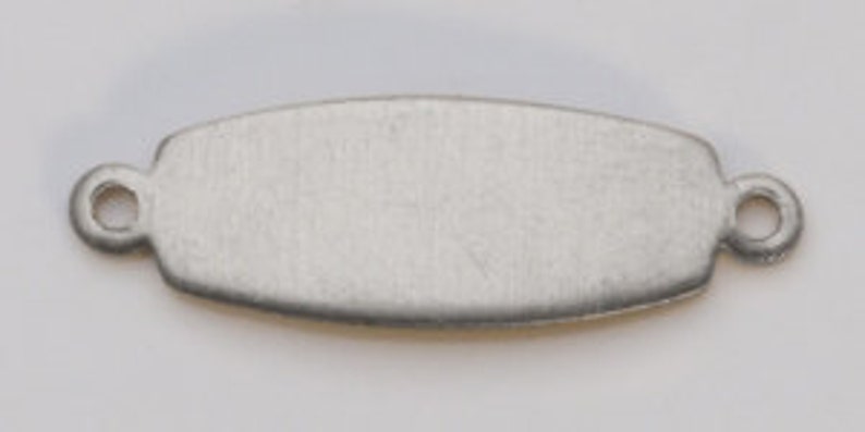 May include: A silver-toned, rectangular metal tag with rounded edges and two small holes on either side. The tag is blank and ready for personalization.