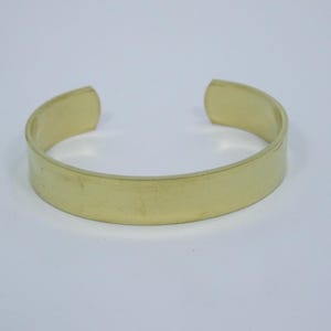 K&ouml;nnte beinhalten: Ein schlichtes, goldfarbenes Metallarmband mit einer glatten, ebenen Oberfl&auml;che.
