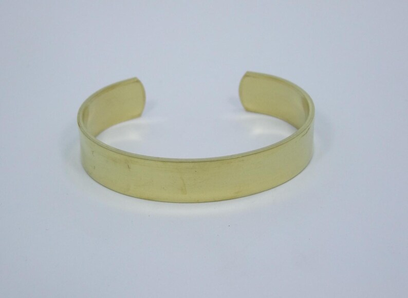 K&ouml;nnte beinhalten: Ein schlichtes, goldfarbenes Metallarmband mit einer glatten, ebenen Oberfl&auml;che.