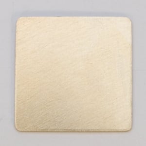 May include: A square piece of brushed metal with a light gold finish.