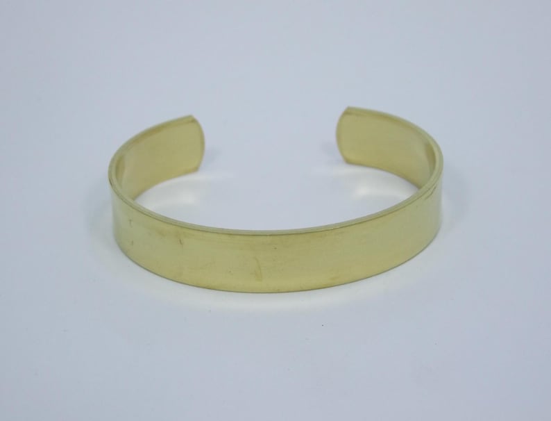 Puede incluir: Una pulsera simple de metal dorado con una superficie lisa y plana.