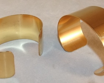 May include: Two gold metal bracelets, one is slightly larger than the other.