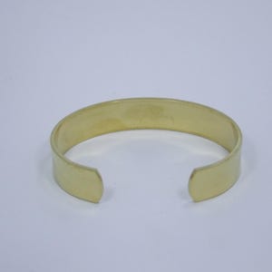 Puede incluir: Un brazalete simple de metal de color dorado. El brazalete est&aacute; abierto en ambos extremos y tiene un acabado liso y pulido.