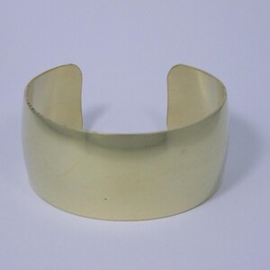 May include: A simple gold-toned metal cuff bracelet. The bracelet is smooth and has a polished finish.