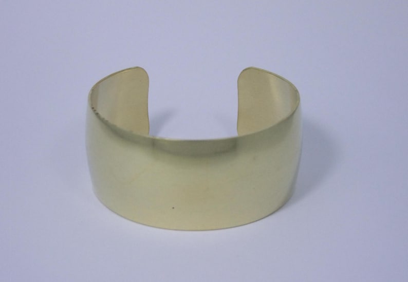 May include: A simple gold-toned metal cuff bracelet. The bracelet is smooth and has a polished finish.