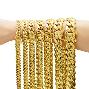 May include: A collection of gold-colored chain necklaces and bracelets with a curb link design. The jewelry pieces vary in size, with a bright, reflective finish. Each piece has a secure clasp.