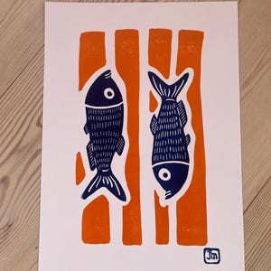 Könnte beinhalten: Ein rechteckiger Druck auf weißem Papier mit zwei dunkelblauen Fischsilhouetten, die in entgegengesetzte Richtungen zeigen und über vier vertikalen orangefarbenen Streifen liegen. In der unteren rechten Ecke befindet sich ein kleiner quadratischer Stempel mit den Buchstaben Jm.