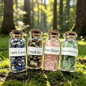 May include: Four clear glass bottles with cork stoppers, each filled with small tumbled gemstones. The labels read Lapis Lazuli, Unakite, Rose Quartz, and Green Aventurine. The bottles contain blue, green, pink, and light green stones respectively.