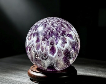 Puede incluir: Una esfera de amatista pulida con inclusiones minerales de color púrpura intenso y blanco translúcido. La piedra se exhibe sobre una base circular de madera de color marrón oscuro, mostrando una superficie lisa y reflectante con patrones cristalinos naturales.