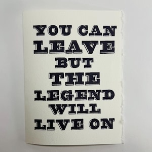 Op de afbeelding: Een rechthoekige gebroken witte kaart met een rafelige rechterrand met de donkerblauw gedrukte tekst: YOU CAN LEAVE BUT THE LEGEND WILL LIVE ON. De letters zijn in een vet, blokkerig schreeflettertype met een klassieke boekdrukuitstraling.