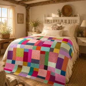 May include: A rectangular quilt featuring a patchwork design of various solid-colored fabric blocks in shades of pink, blue, green, yellow, orange, and purple. The quilt is draped over a bed with white bedding, including pillows and a bed skirt.