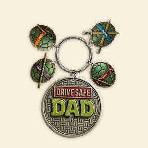 May include: A silver keychain with a "Drive Safe Dad" medallion and four Teenage Mutant Ninja Turtle-themed charms. Each turtle charm has a different coloured mask and weapon, with names on each. A personalised gift.
