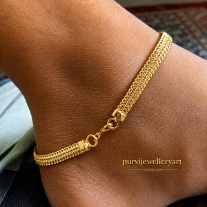 May include: A gold-toned anklet featuring a dense, woven mesh chain design with a polished finish. The piece includes a small circular jump ring connector and a lobster claw clasp mechanism. The text purvijewelleryart is visible on the lower right.