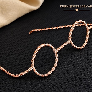 May include: A rose gold-toned wire accessory shaped like a pair of round glasses, crafted from a twisted metal rope design. The piece features two circular frames connected by a bridge, with extended wire arms. Text reads PURVIJEWELLERYART.